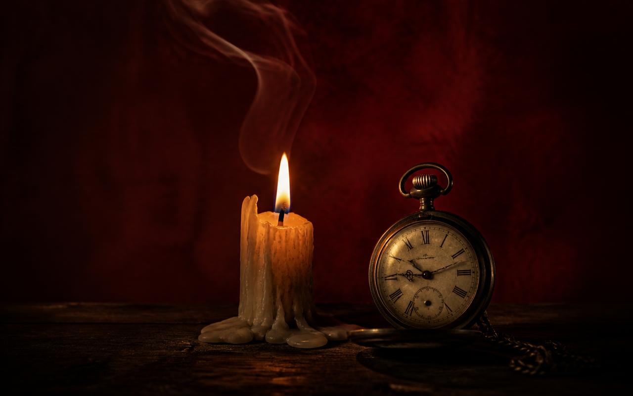 Vela consumiéndose junto a un reloj antiguo